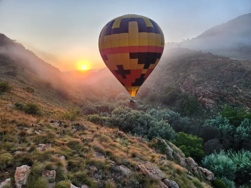 A hot air balloon drifting through a misty valley at sunrise